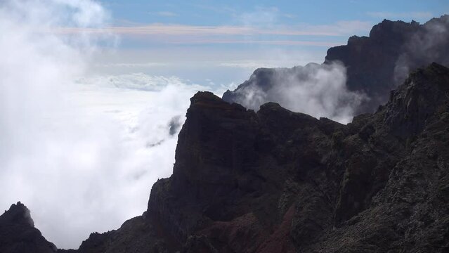 Looking down as the clouds swirl around the black rocks. Real time.