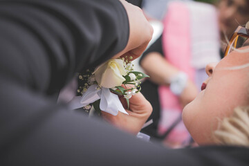 Selective focus shot of a woman pins a corsage on blurred background