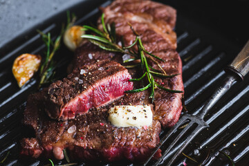beef steak with rosemary on black grill pan, selective focus