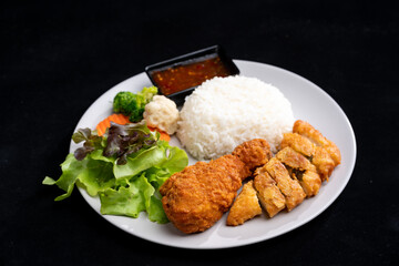 meal food with fried chicken with white rice and vegetable on plate isolated on black background, delicious tasty chicken wing meat