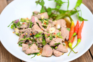 Spicy liver salad on white plate wooden table background, Pork liver salad with fresh chili herbs, spices, Thai food