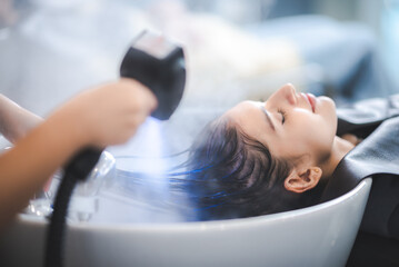 hairdresser washing client's hair at salon. happy young women customer relax and comfortable while...