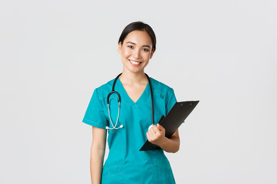 Healthcare workers, preventing virus, quarantine campaign concept. Smiling asian female nurse, doctor with clipboard wearing scrubs, provide checkup, examine patient in clinic, white background