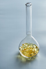 Omega-3 fatty acid capsules on a blue background in a flask. The concept of medicine and healthy living. Vertical photo.