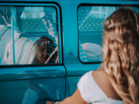 Reflection of a young woman over the glass window of a classic van