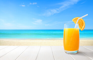Fresh orange juice cocktail on white wood with sandy beach background.