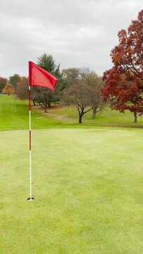 Red flagstick waves on a golf course