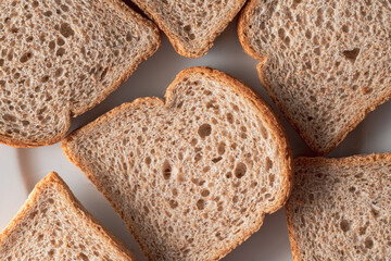 Slices of brown bread baked from wheat flour on a white plate.