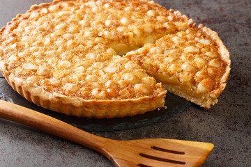 Caramel macadamia tart baked in a buttery homemade shortcrust pastry closeup in the board on the table. Horizontal - obrazy, fototapety, plakaty