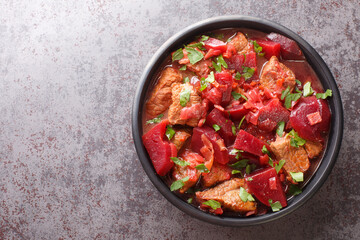 Beef ragout with beets, onions and garlic in red wine close-up in a bowl on the table. horizontal top view from above