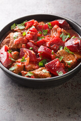 Delicious meat stew with beets and onions in a spicy sauce close-up in a bowl on the table. vertical