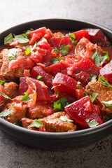 Braised beef with beets and onions in a spicy sauce close-up in a bowl on the table. vertical