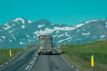 Rear view of an adventure offroad vehicle traveling through icelandic roads towards the mountains. Epic roadtrip with a car or overlanding vehicle.
