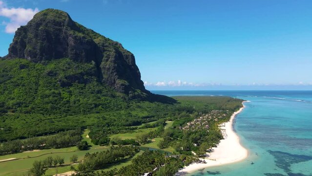 Le Morne beach Mauritius Tropical beach with palm trees and white sand blue ocean and beach beds with umbrellas, sun chairs, and parasols under a palm tree at a tropical beach. Mauritius Le Morne