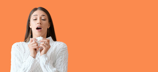 Sneezing young woman on orange background with space for text. Allergy concept