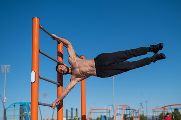 Shirtless man doing human flag outdoors. 