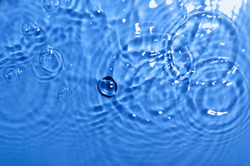 Clean water with splashes on color background