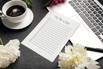 Blank to do list, pen, laptop, cup of coffee and peony flowers on dark table