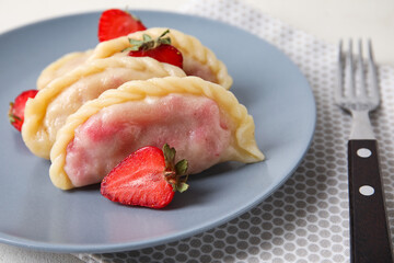 Plate with delicious strawberry dumplings on light background, closeup