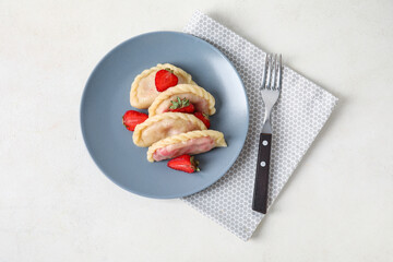 Plate with delicious strawberry dumplings on light background