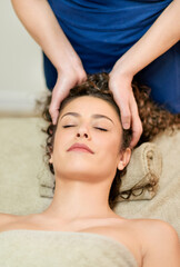 Faceless masseur doing head massage to woman
