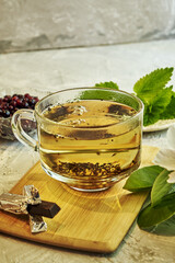 a cup of tea on the table next to chocolate mint a flowering sprig of quince and black currant in a cup