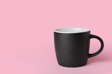 Black ceramic cup on pink background