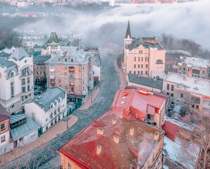 Aerial view of Andriyivskyy Descent, Richard the Lionheart Castle and soft morning fog in Kyiv,...