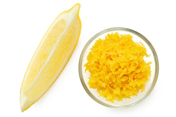 Grated lemon zest in a glass bowl next to lemon segment from above.