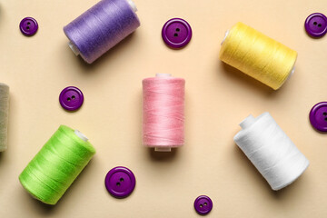 Sewing threads with buttons on beige background