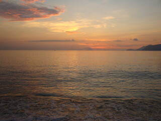 Naklejka na ściany i meble Calm sea at dawn. Small waves roll on the sandy beach.
