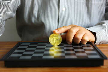 business hand put on index finger on bit coin on chess board
