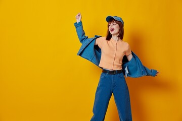 Positive young woman in a cap and denim jacket posing color background unaltered