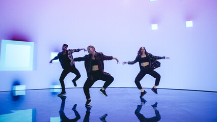 Diverse Group of Three Professional Dancers Performing a Hip Hop Dance Routine in Front of a Big...