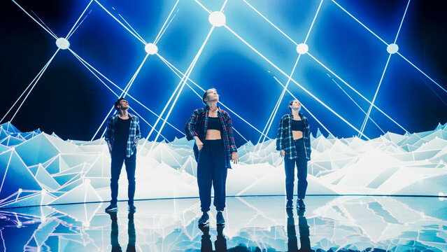 Diverse Group Of Three Professional Dancers Performing A Hip Hop Dance Routine In Front Of A Big Led Wall Screen With VFX Animation During A Virtual Production In Studio Environment. 105 BPM Song.