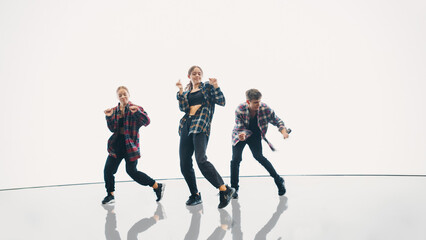Diverse Group of Three Professional Dancers Performing a Hip Hop Dance Routine in Front of a Big Digital Led Wall Screen with Bright White Background in Studio Environment.