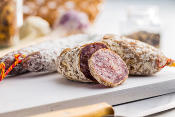 Traditional sausage with white mold. Dried sliced pork salami on cutting board.