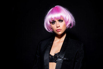 Fototapeta premium Close-up portrait of young woman with pink bob cut and stylish makeup isolated on black.