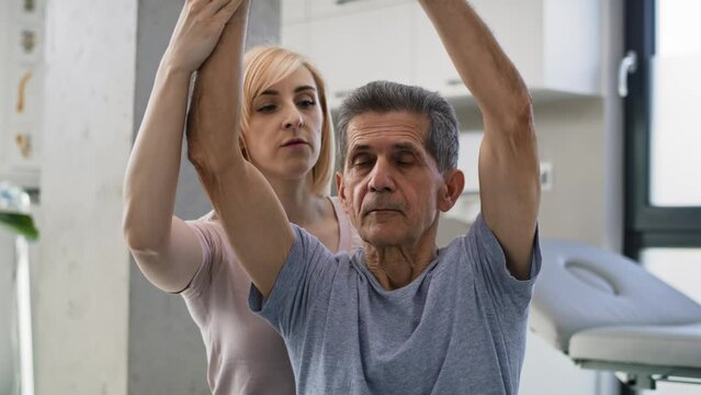 Female physical therapist working with senior man at doctor's office. Shot with RED helium camera in 8K.    