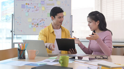 Young creative woman explaining new project and discussing corporate business plan with her colleague.