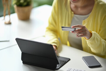 Fototapeta premium Cropped shot woman holding credit card and using internet banking service on computer tablet.