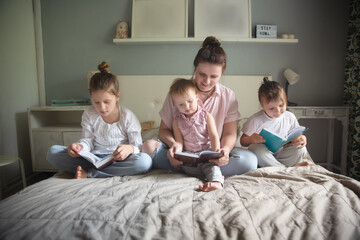 Mom with children in the bedroom reading a book, lifestyle