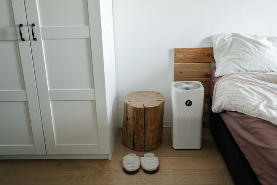 Technologies for health. The air purifier stands on the floor in the bedroom next to the bed and cleans the air of dust.