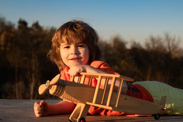Dreams of flight. Child playing with toy plane against the sky. Dreams of travels. Little dreaming child with a toy airplane plays outdoors. Summer holidays with children.
