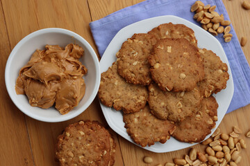 Peanut butter cookies on a plate with peanuts and peanut butter cream on wooden table Traditional american dessert 