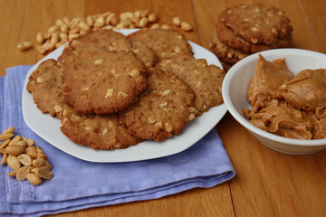 Peanut butter cookies on a plate with peanuts and peanut butter cream on wooden table Traditional american dessert 