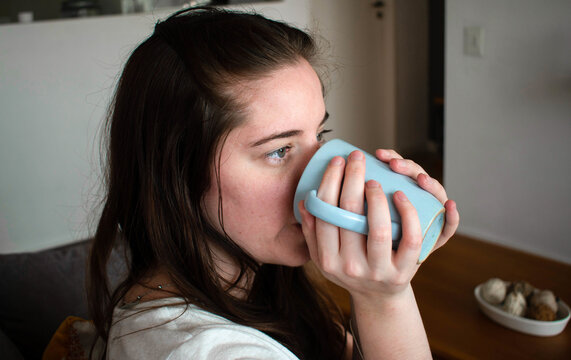 Closeup Shot Of A Young Brunette Female Drinking Out Of A Mug At Home