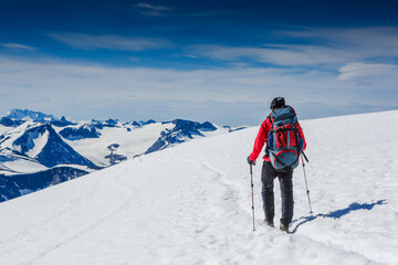 Fototapeta na wymiar Hiker with backpack walking on snowy trail in Norway