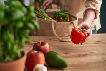 Woman holding paprika and other vegetables from shopping bag