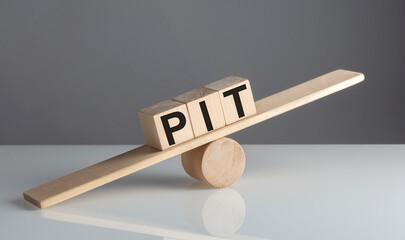 PIT on wooden cubes on a wooden balance , business concept